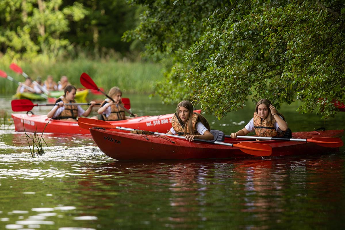 Dzieci spędzają czas w kajakach na obozie nad jeziorem w Smerzynie